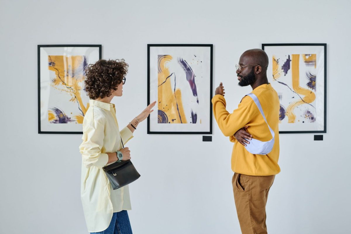 Two people discuss paintings in a gallery. 